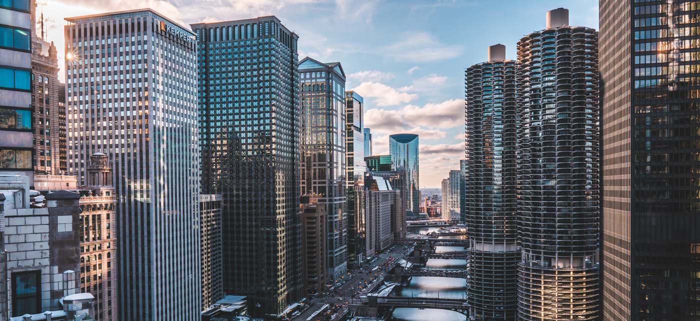commercial real estate illinois aerial daytime view of bridges over chicago river with lines of office buildings either side of the river shimmering with reflected sunlight image at offices.net