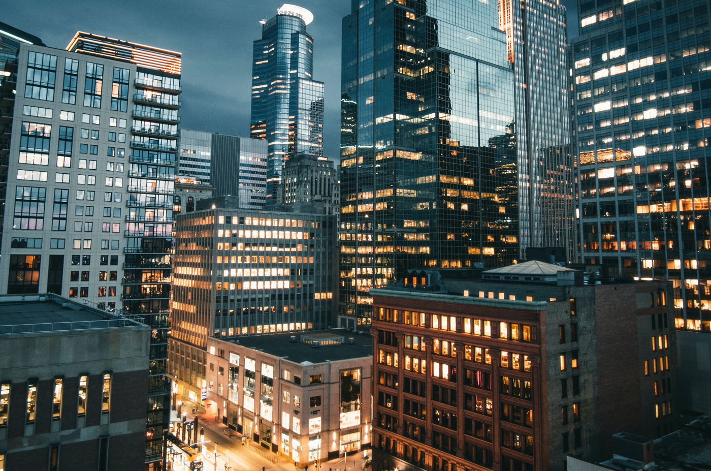 Minneapolis high rise buildings lit up, under a dark evening gray cloudy sky.