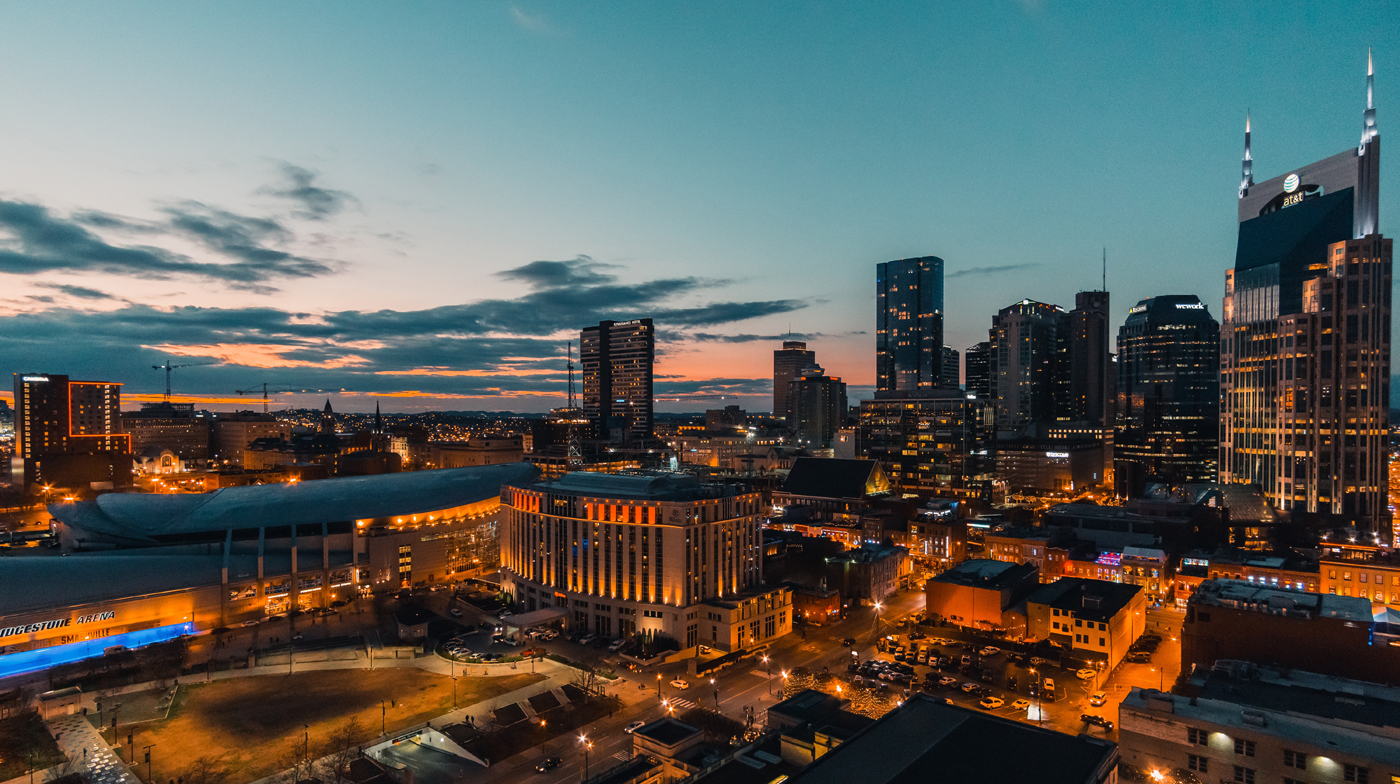 dusk view of nashville city skyline commercial real estate tennessee office buildings with lights on and the background sky still orange near the horizon post sunset